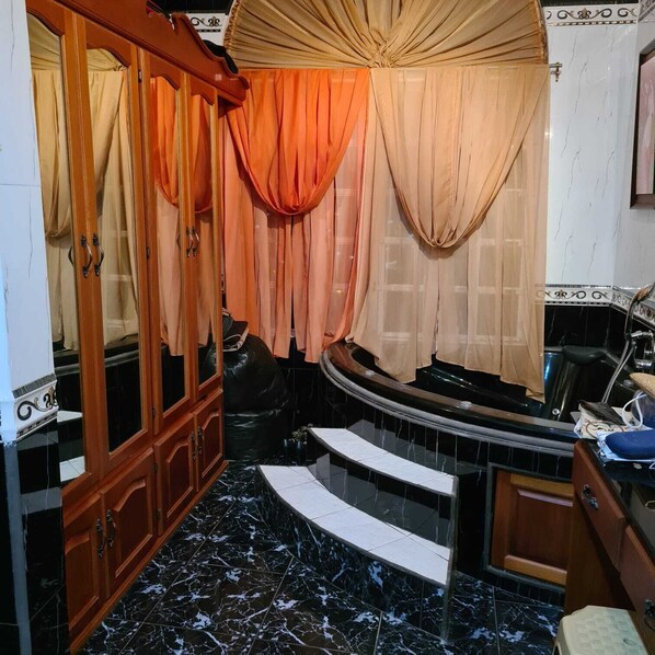 A bathroom with a curved sink, wooden cabinets, and marble flooring. - QBR Balcony Suite (St. Joseph)
