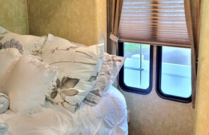 A bed with floral-patterned pillows, a window with blinds, and a view of a building outside. - Private 2 bedroom 2 bathroom whole home dog friendly quiet Hideaway in Tampa Bay (Lutz)