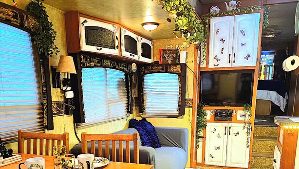 A compact living space with a dining area, a sofa, a TV, and a kitchenette.