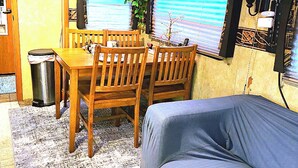 A compact RV interior with a dining area, a sofa, and a trash can.