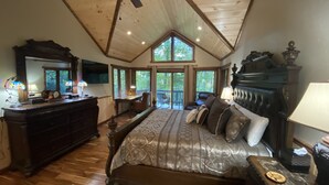 A spacious bedroom with a large bed, a dresser, a vanity, and a ceiling fan.