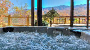 A hot tub with a view of autumn trees and mountains.