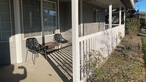 A covered porch with two chairs and a bench, white railings, and a small garden area. - Peaceful Ranch-style Single level 3B Retreat (Hillsboro)