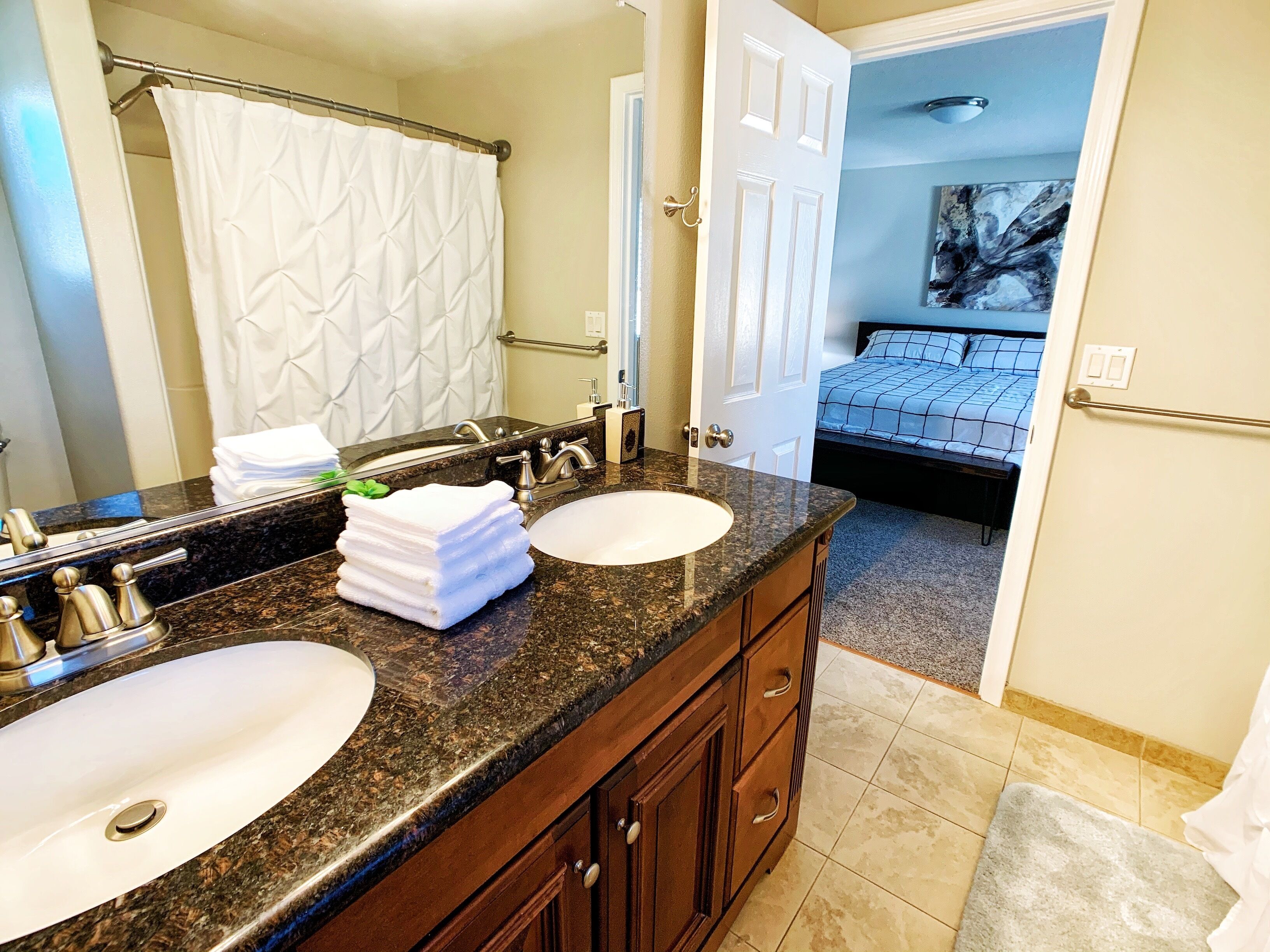 A bathroom with two sinks, a mirror, and a towel rack.