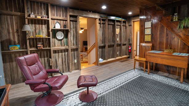 Un interior de madera con una butaca de cuero, un taburete pequeño y una mesa de madera.