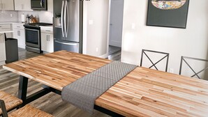 Een moderne keuken met roestvrijstalen apparatuur, een houten eettafel en een beklede bank.