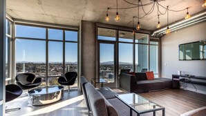 Una sala de estar moderna con vistas panorámicas a la ciudad, grandes ventanales y muebles contemporáneos.