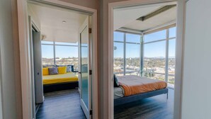 Un dormitorio moderno con cama, sofá y un amplio ventanal con vistas a la ciudad.