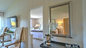 A hotel room with a bed, a sitting area with a chair and a small table, a large mirror, and a view of the garden through the window. - Condo on pond w/2 Fishing Badges, 24 Mi. to Aspen! (Carbondale)