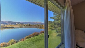 A room with a large window overlooking a lake and a grassy area with trees. - Condo on pond w/2 Fishing Badges, 24 Mi. to Aspen! (Carbondale)