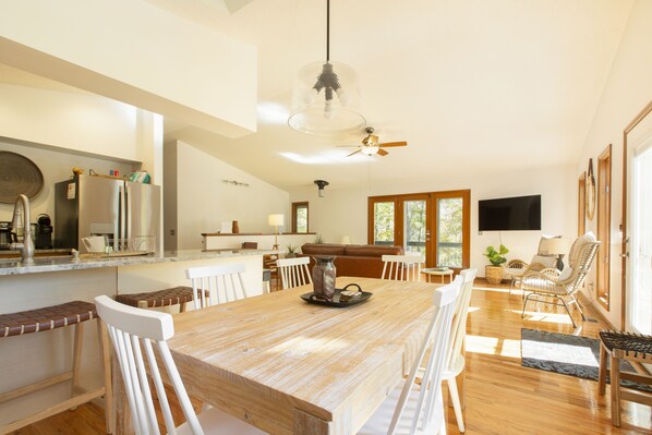 Una cocina amplia con una isla central, sillas blancas y una mesa de comedor.