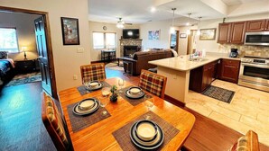 A spacious living area with a dining table set for six, a kitchen with modern appliances, and a cozy seating area with a fireplace. - HV 102, great view, Handicapped accessible (Gatlinburg)