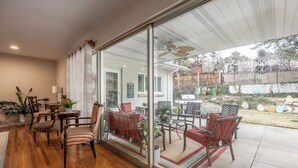 A patio with a glass door leading to a backyard, wooden flooring, and outdoor furniture.