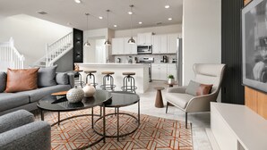 A modern living room with a gray sofa, a coffee table, and a patterned rug.