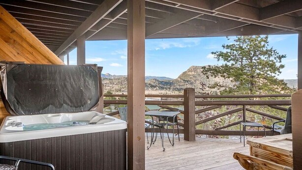 A hot tub on a wooden deck with a view of a mountainous landscape.