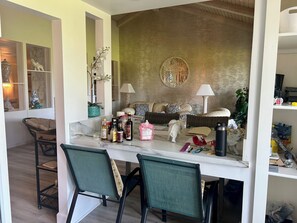 Un accogliente soggiorno con divano, poltrone, tavolino e una parete decorativa.