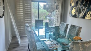 A dining area with a glass table, patterned chairs, a chandelier, and a view of greenery outside. - Private 2 Bed 2 .5 Baths Spacious Condo (Palm Desert)
