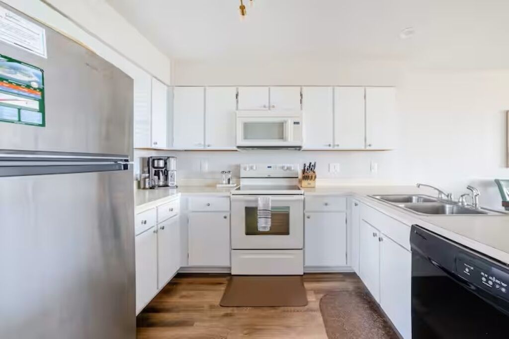 A modern kitchen with white cabinets, a microwave, an oven, and a dishwasher.