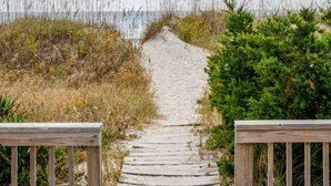 A wooden boardwalk leading to a beach, surrounded by vegetation. - Toes in the Sand 🏖 Drink in Hand!  2 Decks, Views throughout, Great location! (Emerald Isle)