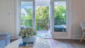 Ein Zimmer mit einer Schiebeglastür, die auf einen Balkon mit Blick auf Grünflächen und Geländer führt.