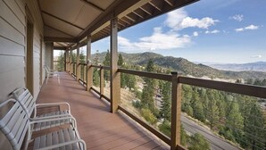 Ein überdachter Balkon mit Holzgeländern und Bänken, mit Blick auf eine Berglandschaft.