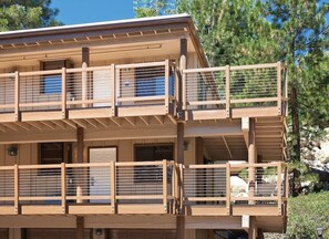 A multi-story building with balconies, wooden railings, and a clear view of the surrounding trees.