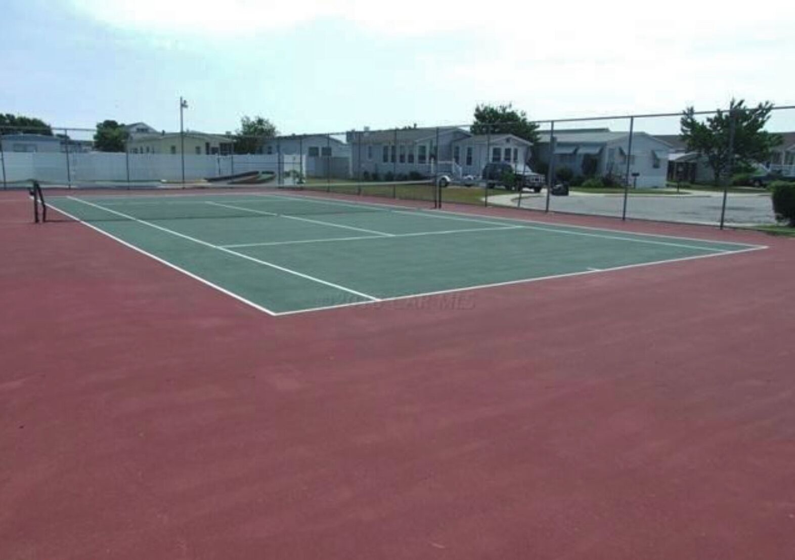 Un court de tennis avec une surface rouge et des lignes de démarcation blanches.