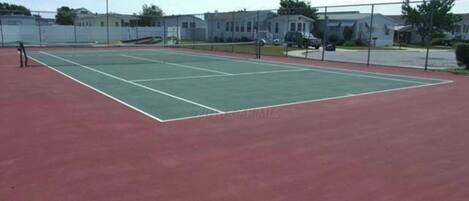 Un court de tennis avec une surface rouge et des lignes de démarcation blanches.