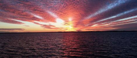 Un atardecer sobre un cuerpo de agua con un horizonte despejado.