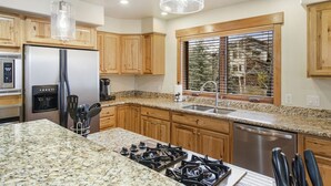 A modern kitchen with granite countertops, wooden cabinets, a stainless steel refrigerator, a built-in oven, and a dishwasher. - Quiet - Spacious- On Ski Bus Line - Community Hot Tubs - WD (Steamboat Springs)