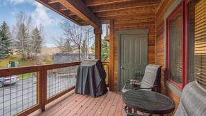 A wooden deck with a table and chairs, a covered table, and a door. - Quiet - Spacious- On Ski Bus Line - Community Hot Tubs - WD (Steamboat Springs)