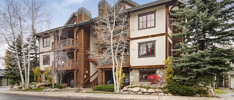 A multi-story house with a stone facade, wooden balconies, and a stone foundation.