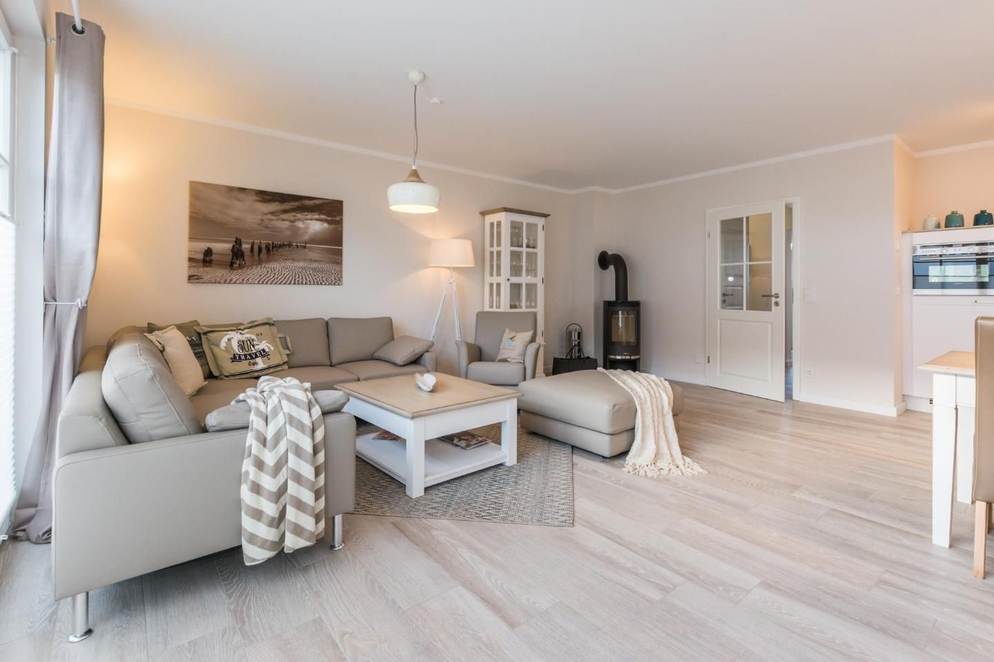 Un salon moderne comprenant un canapé, une table basse, une lampe, une cheminée et un coin cuisine.