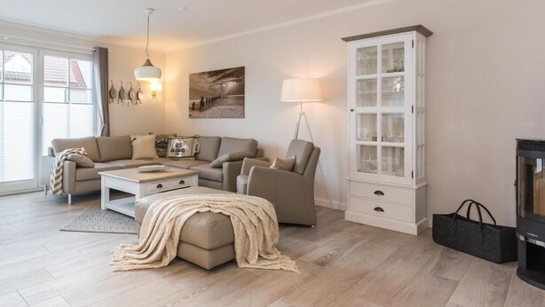 A living room with a sofa, armchair, ottoman, coffee table, and a cabinet.