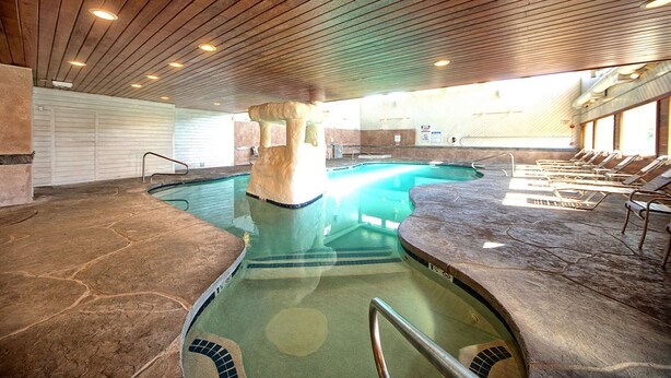 Una piscina interior con suelo de piedra y sillones de descanso.