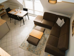 En moderne stue med sofa, sofabord, spisebord med stole og et stort vindue.