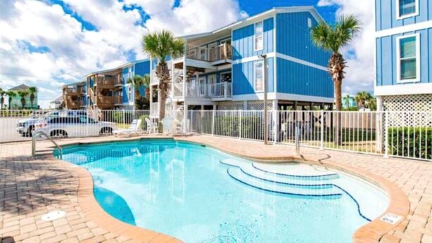 A swimming pool with a tiled deck, surrounded by a white fence. - Seahorse 512- Seahorse Condos (Gulf Shores)