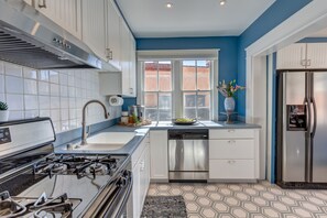 Una cocina moderna con armarios blancos, electrodomésticos de acero inoxidable y una pared de acento azul.