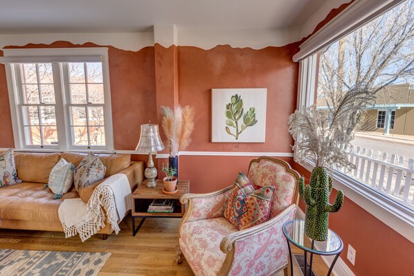 Una sala acogedora con pared marrón, una ventana, un cactus y un sofá.