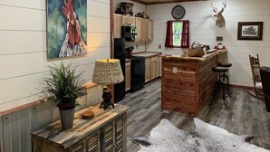 Una cocina rústica con armarios de madera, un reloj y una cabeza de venado montada en la pared.