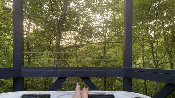 Un jacuzzi con terraza de madera y vista al bosque.