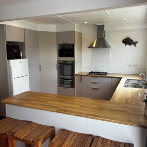Una cocina moderna con encimera de madera, electrodomésticos integrados y decoración de pared con motivos marinos.