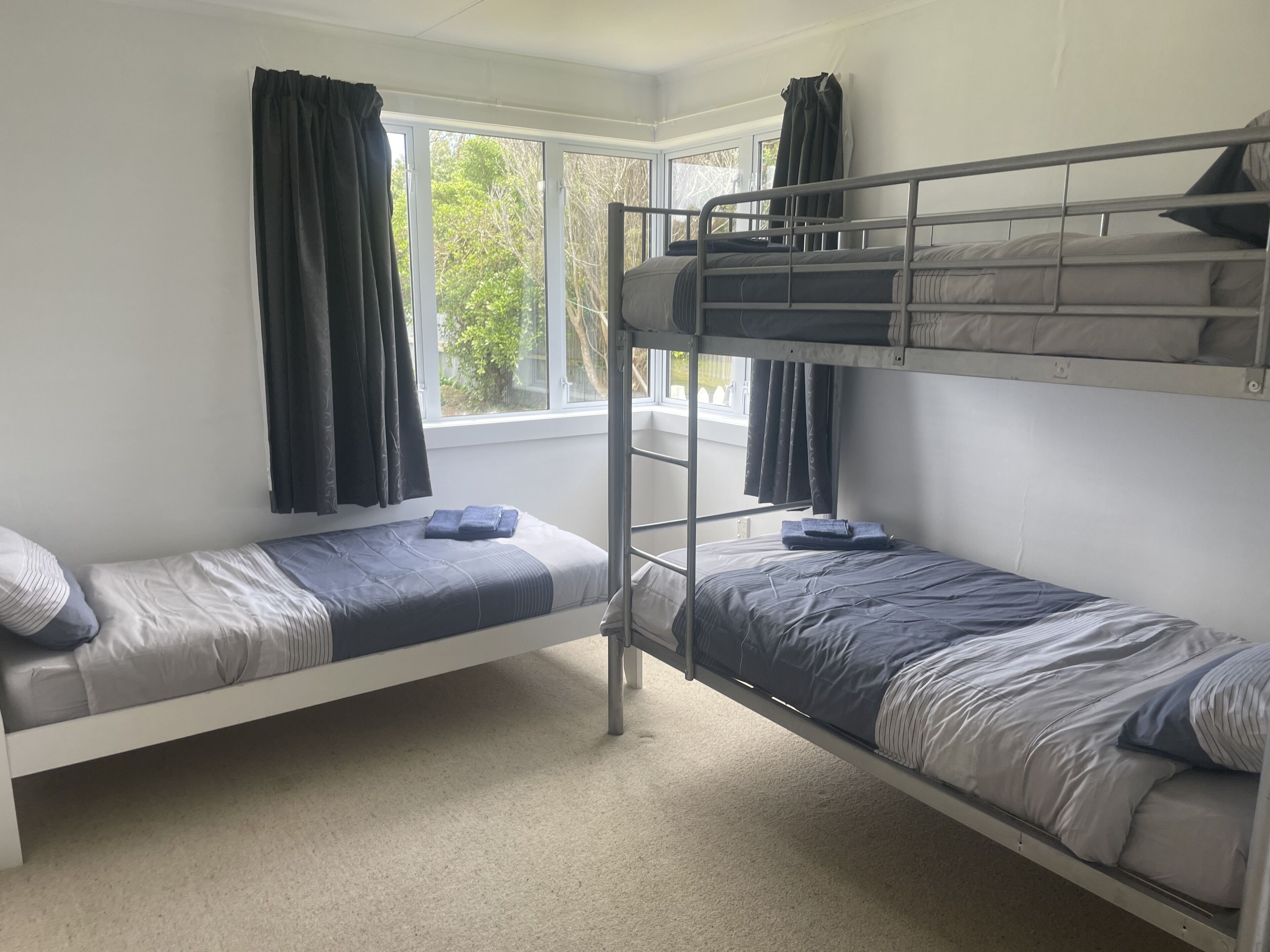 Une chambre de dortoir avec des lits superposés, une fenêtre avec des rideaux et un sol recouvert de moquette.