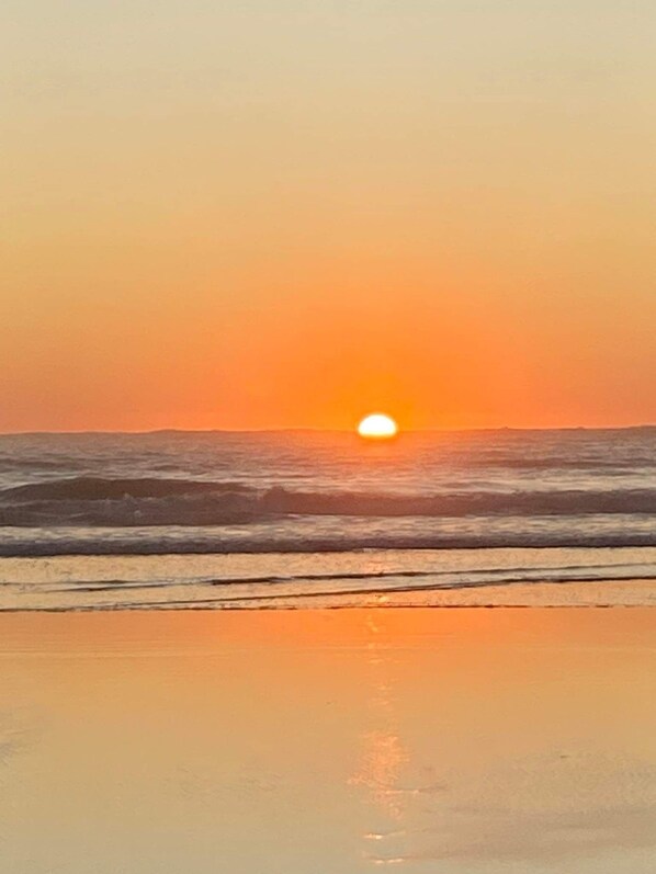 Una playa con un atardecer sobre el océano.