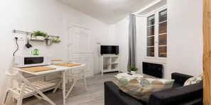 A compact living space with a kitchenette, a dining area, a seating area with a sofa, and a television.