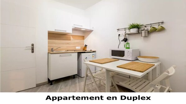 A compact kitchen with white cabinets, a microwave, and a small refrigerator.