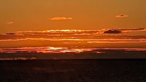 Um pôr do sol sobre uma paisagem plana com horizonte nítido.