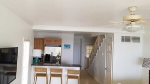 A kitchen with a refrigerator, a dining area with chairs, and a ceiling fan. - Silver Sand Villa 7A (Cotton Ground)