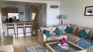 A living room with a beige sofa, a glass coffee table, and a patterned rug. - Silver Sand Villa 7A (Cotton Ground)