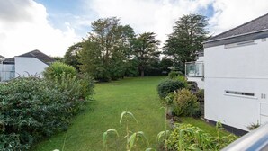 A residential garden with a lawn, various shrubs, and trees. - 25 Coedrath Park - Sea Views From Balcony Short Walk to Beach Parking (Saundersfoot)